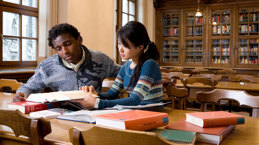Zwei Studierende in einer Bibliothek.